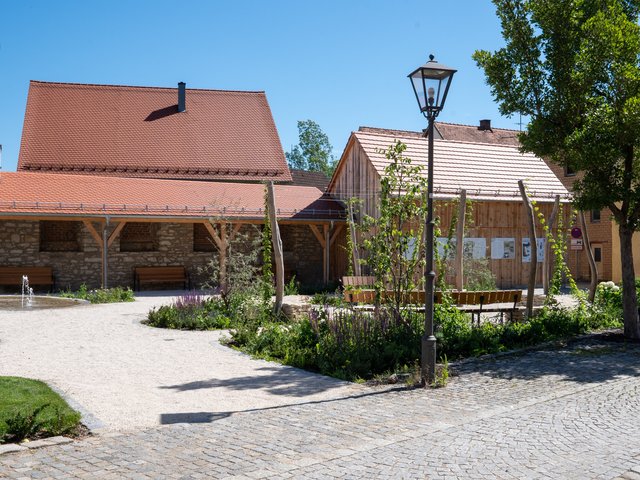 Hopfengarten im Hintergrund Laubengang und Stadl mit Info-Tafeln zur Entstehung und Geschichte