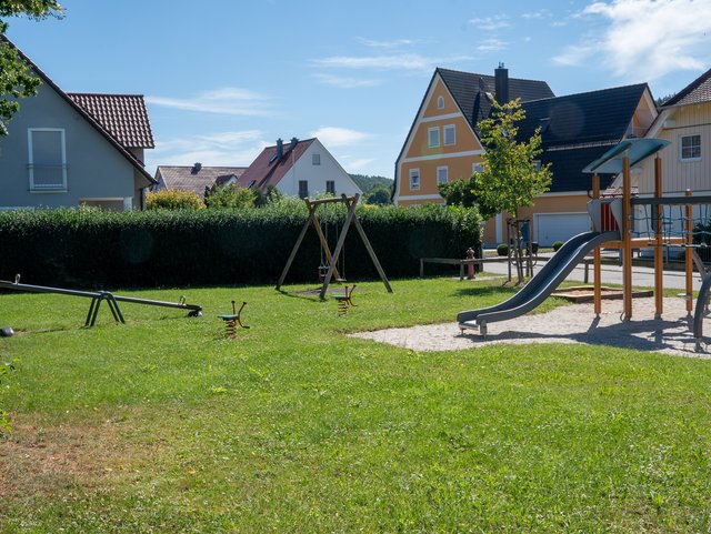 Wippe, Schaukel, Wipptiere und Teil des Kletterturms am Spielplatz 